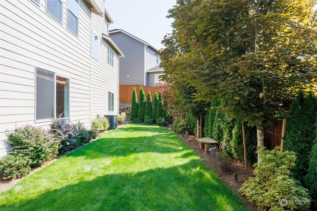 view of yard with central AC and fence