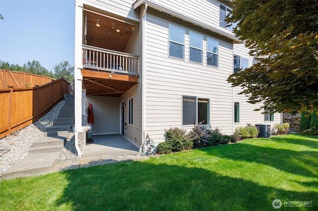 rear view of property featuring fence, stairway, central AC, a yard, and a patio area