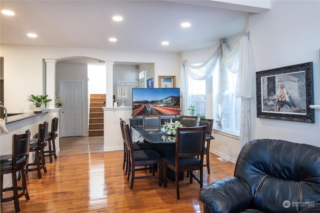 dining area featuring wood-type flooring and decorative columns