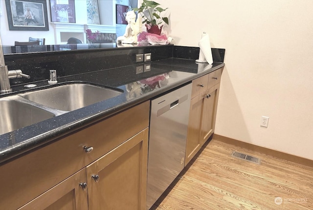 kitchen featuring dishwasher, sink, dark stone countertops, and light hardwood / wood-style flooring