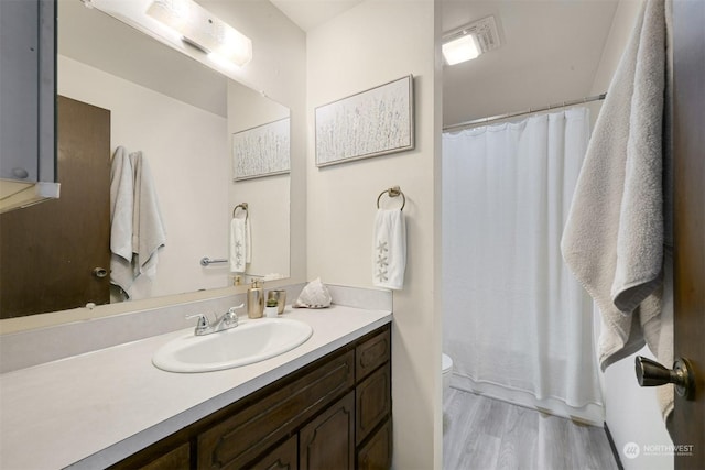 bathroom with vanity, hardwood / wood-style flooring, a shower with shower curtain, and toilet