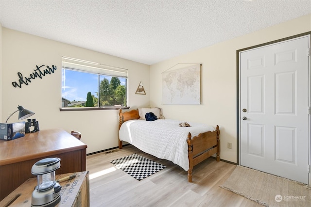 bedroom featuring a textured ceiling and light hardwood / wood-style flooring