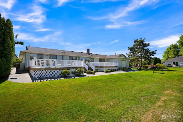 rear view of house featuring a wooden deck and a yard