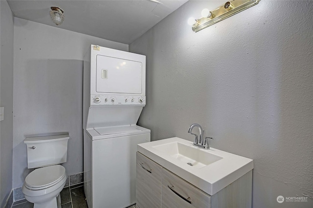 bathroom featuring vanity, stacked washer / drying machine, tile patterned floors, and toilet