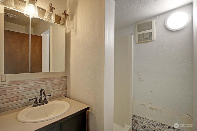 bathroom with vanity, backsplash, and a textured ceiling