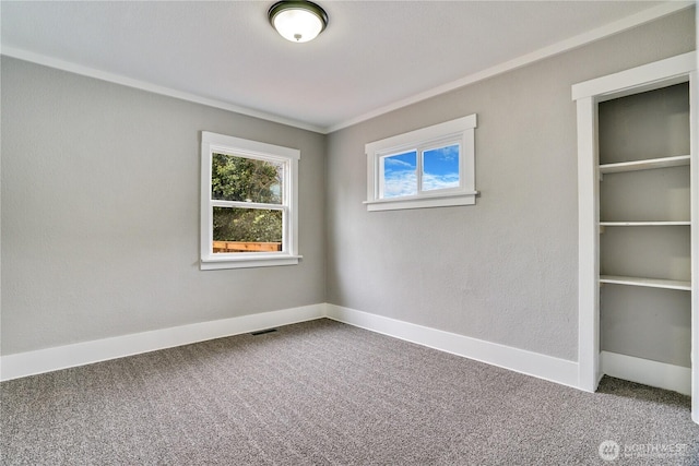 empty room with carpet floors, ornamental molding, and baseboards
