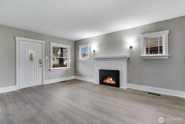 unfurnished living room featuring wood finished floors, a fireplace, and baseboards