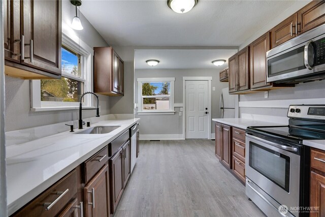 kitchen featuring appliances with stainless steel finishes, a sink, light wood-type flooring, and healthy amount of natural light