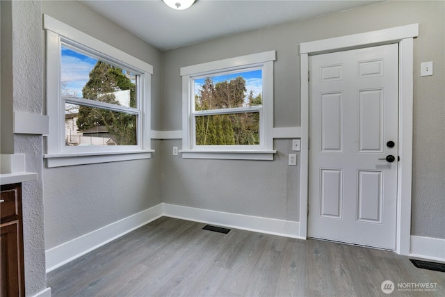 entryway featuring wood finished floors, baseboards, and a textured wall