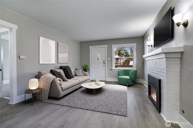living area featuring a fireplace, wood finished floors, and baseboards