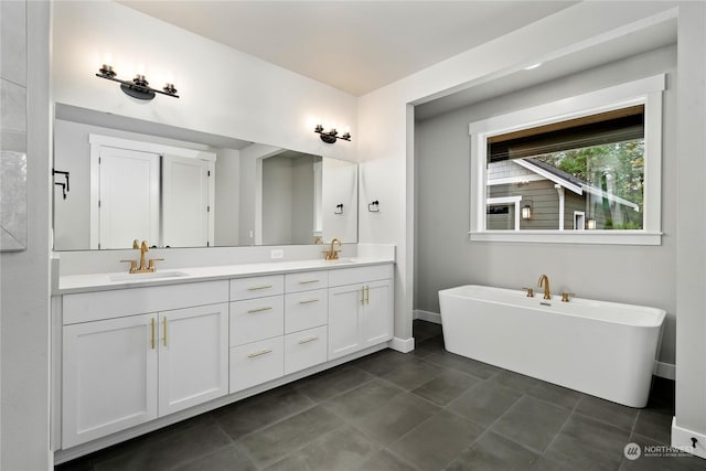 bathroom with a tub to relax in, vanity, and tile patterned floors