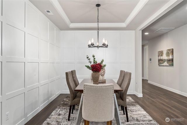 dining space with a tray ceiling, dark hardwood / wood-style floors, and a notable chandelier