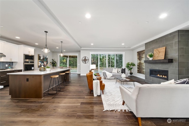 living room with dark wood-type flooring and a tiled fireplace