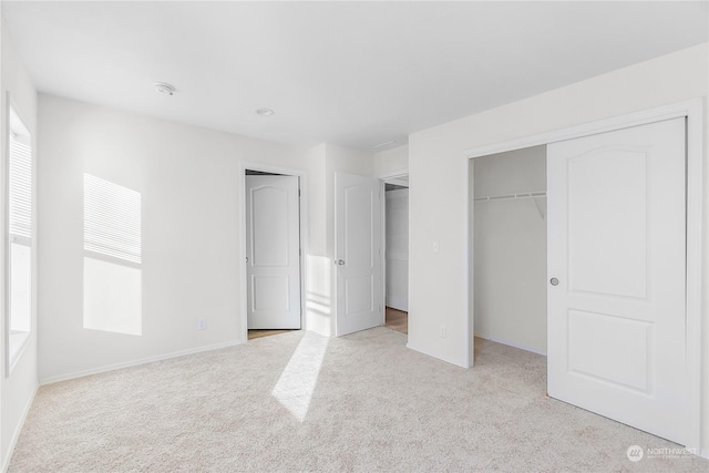 unfurnished bedroom with multiple windows, light colored carpet, and a closet