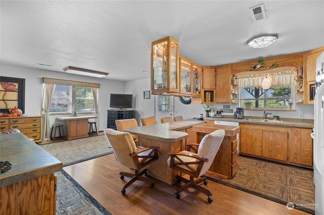 kitchen featuring kitchen peninsula, light hardwood / wood-style floors, sink, and a textured ceiling