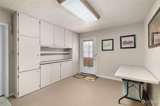 kitchen with a textured ceiling and white cabinets