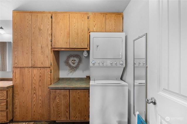 laundry room featuring stacked washer / drying machine and cabinets