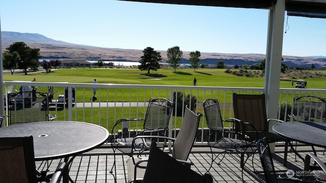 wooden deck with a mountain view and a lawn