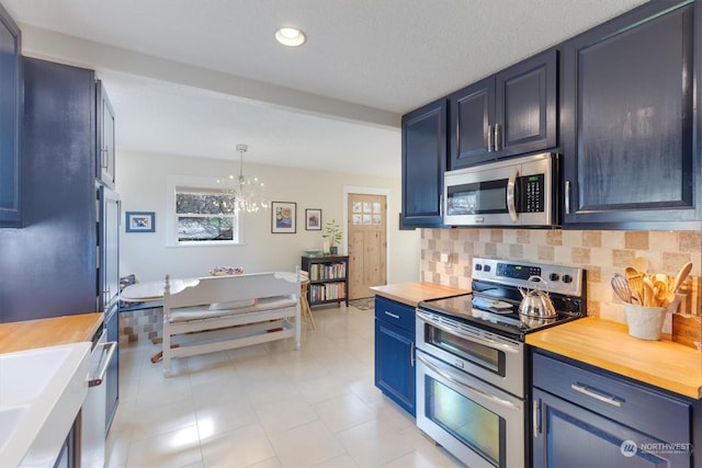 kitchen featuring blue cabinets, hanging light fixtures, backsplash, and appliances with stainless steel finishes