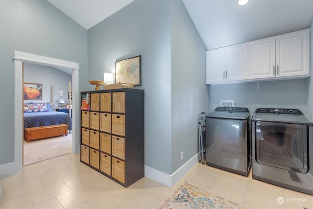 laundry area featuring washer and dryer, light tile patterned floors, and cabinets