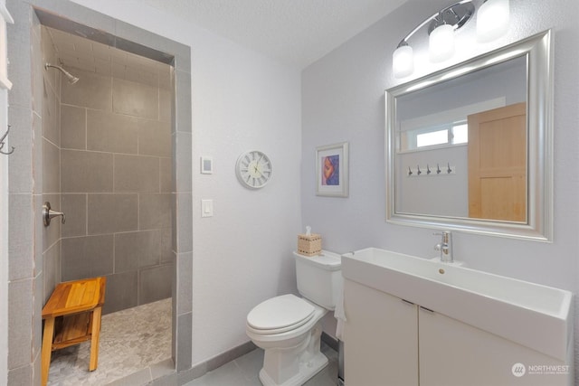 bathroom with tiled shower, tile patterned floors, toilet, a textured ceiling, and vanity