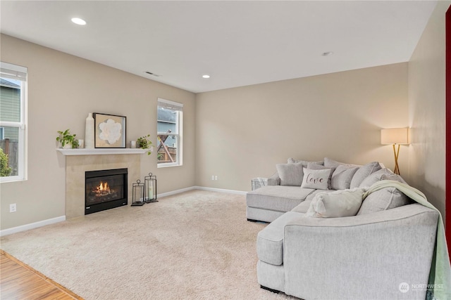 living room with a tile fireplace, a healthy amount of sunlight, and hardwood / wood-style floors