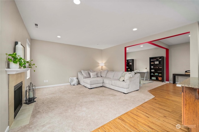 living room featuring a tile fireplace and light hardwood / wood-style flooring