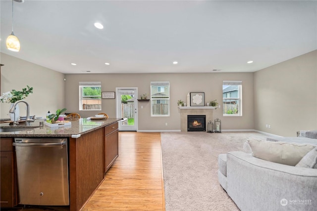 kitchen with stainless steel dishwasher, decorative light fixtures, sink, and a wealth of natural light