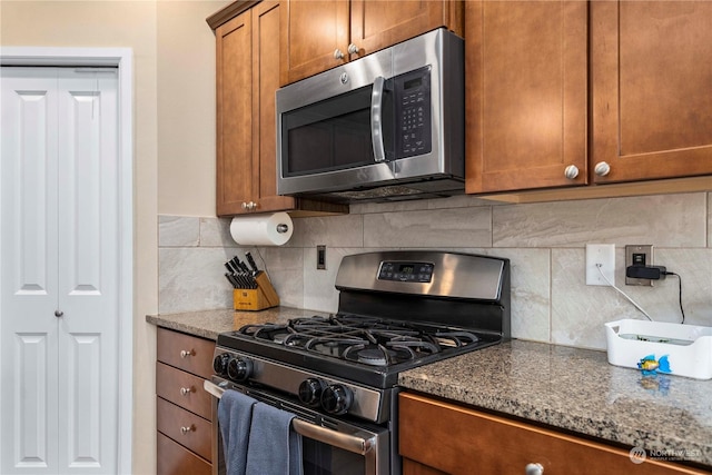 kitchen with dark stone countertops, decorative backsplash, and stainless steel appliances