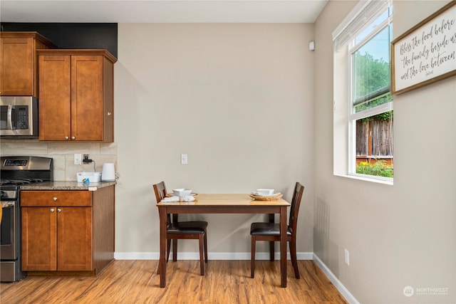 kitchen with light stone countertops, decorative backsplash, stainless steel appliances, and light hardwood / wood-style floors