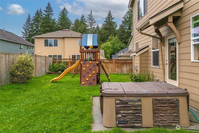 view of jungle gym featuring a lawn and a hot tub