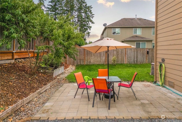 patio terrace at dusk featuring a lawn