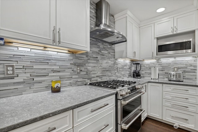 kitchen featuring stone countertops, tasteful backsplash, white cabinets, stainless steel appliances, and wall chimney exhaust hood