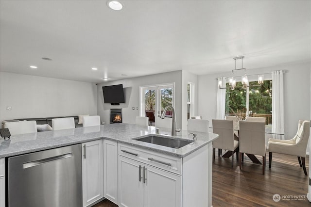 kitchen with sink, light stone counters, stainless steel dishwasher, pendant lighting, and white cabinets