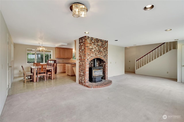 unfurnished living room with a wood stove, light colored carpet, and a chandelier