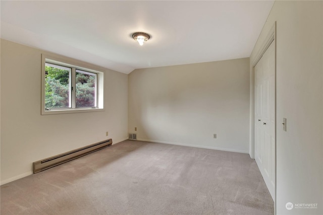 unfurnished bedroom featuring a baseboard heating unit, a closet, vaulted ceiling, and light carpet