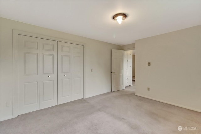 unfurnished bedroom featuring light carpet and a closet