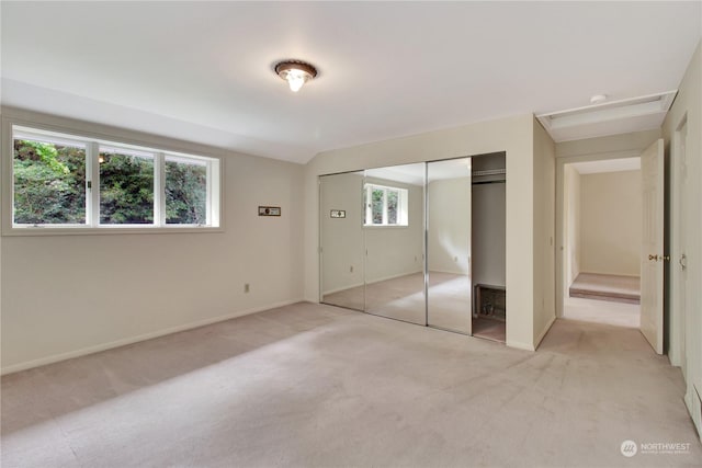 unfurnished bedroom featuring light carpet, a closet, multiple windows, and lofted ceiling