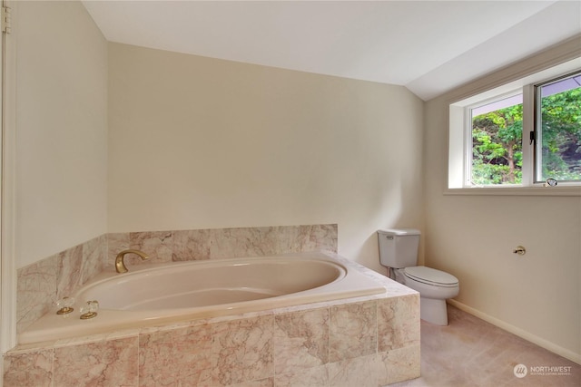 bathroom with toilet, vaulted ceiling, and tiled tub