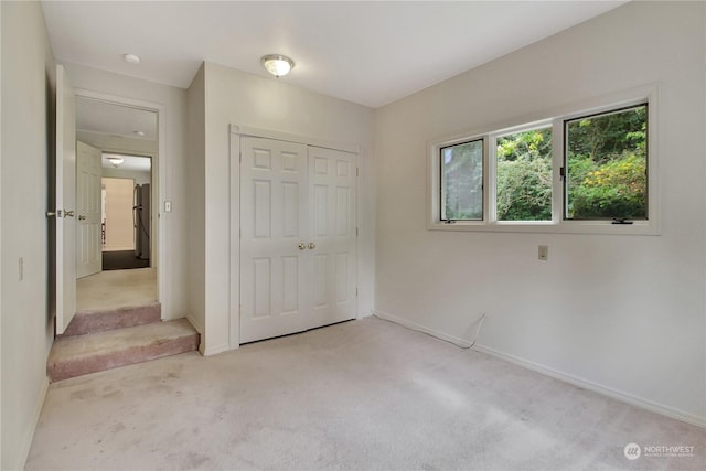 unfurnished bedroom with a closet and light carpet