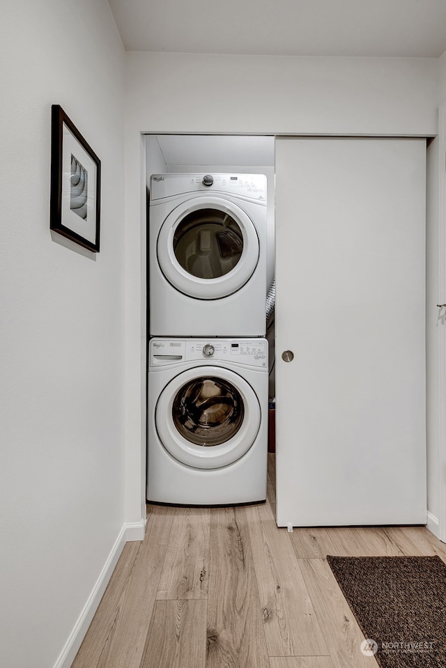 laundry area with light hardwood / wood-style flooring and stacked washer / dryer