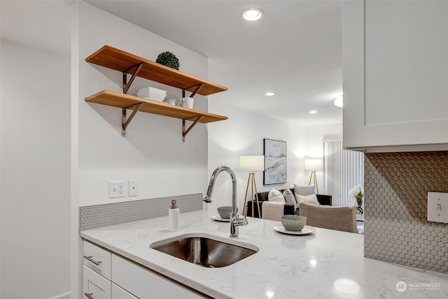 kitchen with light stone counters, sink, and white cabinets