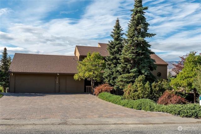 view of front of property featuring a garage, a shingled roof, and decorative driveway