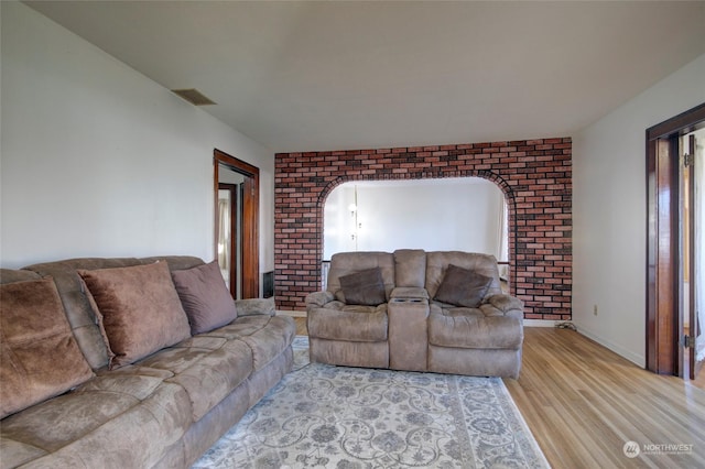 living room with brick wall and light wood-type flooring