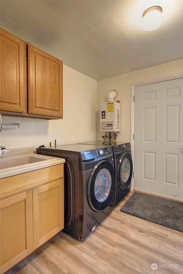 laundry room featuring water heater, cabinets, washing machine and dryer, and light hardwood / wood-style floors