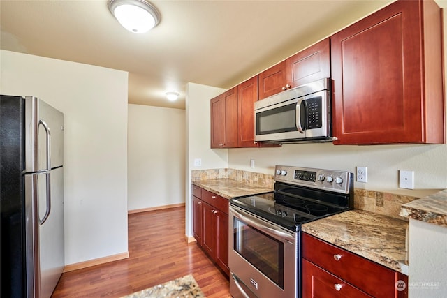 kitchen with light stone countertops, light hardwood / wood-style flooring, and stainless steel appliances