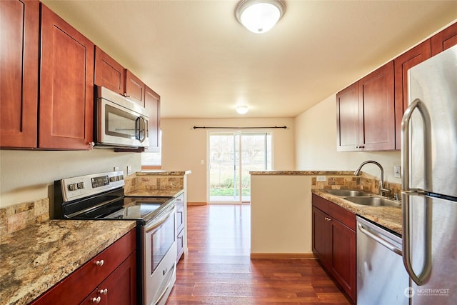 kitchen with light stone countertops, dark hardwood / wood-style floors, sink, and stainless steel appliances