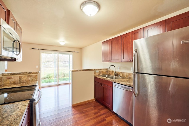 kitchen with light stone counters, sink, appliances with stainless steel finishes, and dark wood-type flooring