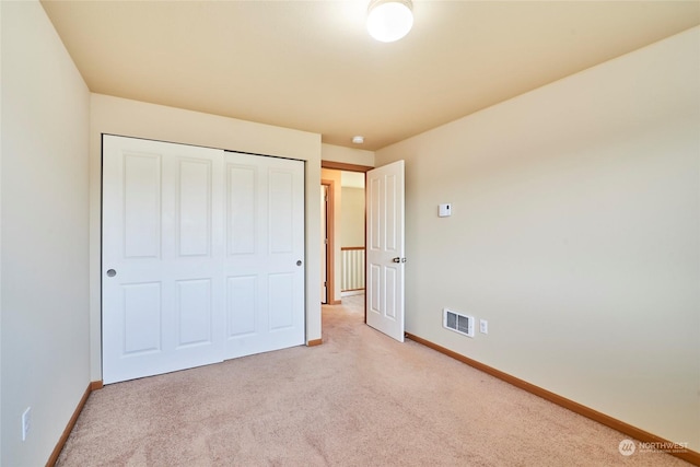 unfurnished bedroom featuring light colored carpet and a closet