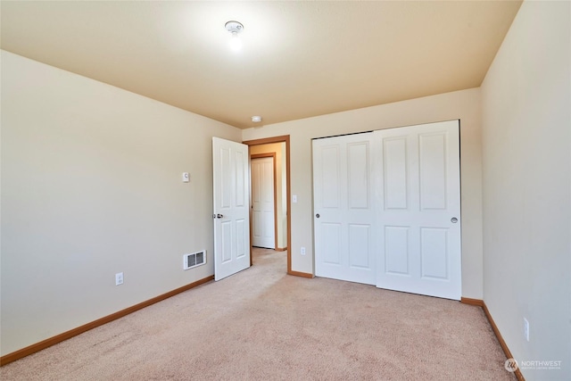 unfurnished bedroom featuring light colored carpet and a closet